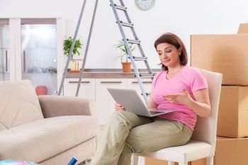 Middle-aged woman with laptop in home improvement concept 
