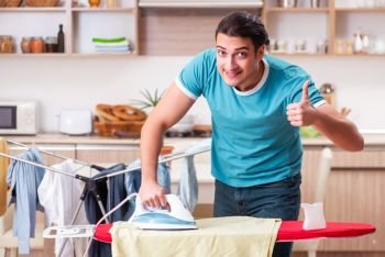 Young man husband doing clothing ironing at home 