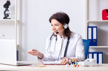 Middle-aged female doctor in telemedicine concept 
