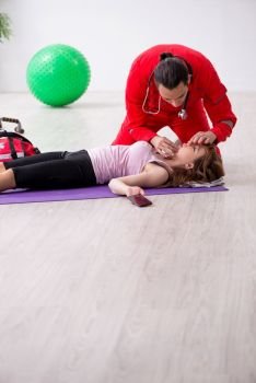 The paramedic in red visiting young woman in gym . Paramedic in red visiting young woman in gym 