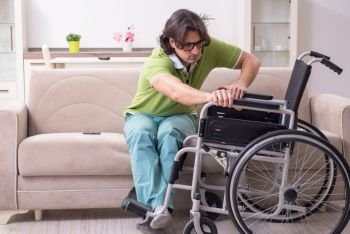 Young male invalid in wheelchair suffering at home