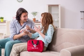 The young couple in first aid concept at home . Young couple in first aid concept at home 