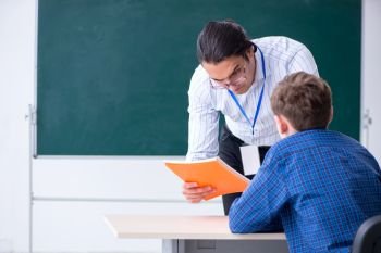 The young male teacher and boy in the classroom . Young male teacher and boy in the classroom 
