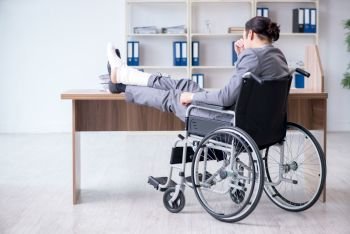 The male employee in wheel-chair in the office . Male employee in wheel-chair in the office 