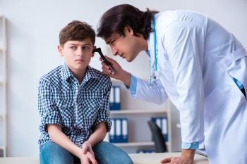 The male otolaryngologist examining boy’s ear . Male otolaryngologist examining boy’s ear 