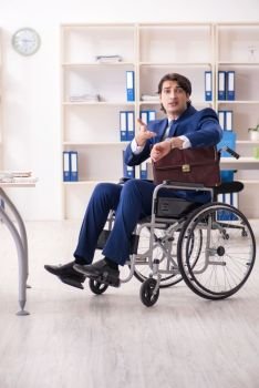 The young male employee in wheelchair working in the office. Young male employee in wheelchair working in the office
