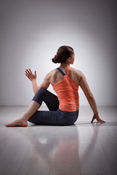 Beautiful sporty fit yogini woman practices yoga asana ardha matsyendrasana - half spinal twist pose. Sporty fit yogini woman practices yoga asana