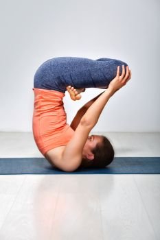 Sporty fit yogini woman practices inverted yoga asana Urdhva padmasana - lifted lotus pose. Woman practices inverted yoga asana