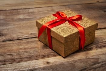 Gift present birthday Christmas concept - gift box with red ribbon on wooden background. Gift box with red ribbon