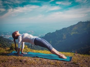 Woman doing Hatha yoga asana Purvottanasana plank pose  outdoors in mountains. Vintage retro effect filtered hipster style image.. Woman doing Hatha yoga asana Purvottanasana