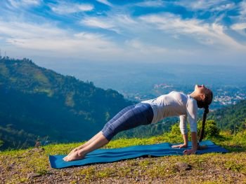 Woman doing Hatha yoga asana Purvottanasana plank pose  outdoors in mountains. Woman doing Hatha yoga asana Purvottanasana