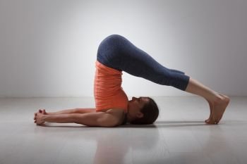 Beautiful sporty fit yogini woman practices yoga asana Halasana - plow pose. Sporty woman practices yoga asana Halasana