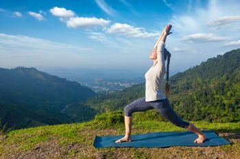 Yoga outdoors - sporty fit woman doing yoga asana Virabhadrasana 1 - Warrior pose posture outdoors in Himalayas mountains in the morning. Woman doing yoga asana Virabhadrasana 1 - Warrior pose outdoors