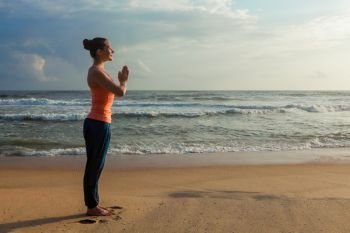 Woman doing Ashtanga Vinyasa Yoga asana Tadasana Samasthiti yoga posture on beach. Woman doing yoga on beach