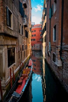 Narrow canal between colorful old houses with gondola boat in Venice, Italy. Narrow canal with gondola in Venice, Italy
