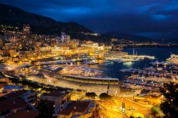 Aerial view of Monaco Monte Carlo harbour and illuminated city skyline in the evening blue hour twilight. Monaco Port night view with luxurious yachts. View of Monaco in the night