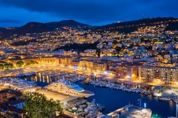 View of Old Port of Nice with luxury yacht boats from Castle Hill, France, Villefranche-sur-Mer, Nice, Cote d’Azur, French Riviera in the evening blue hour twilight illuminated. View of Old Port of Nice with yachts, France in the evening