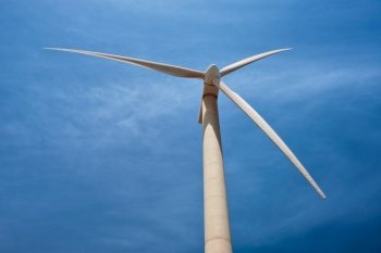 Green renewable alternative energy concept - wind generator turbine generating electricity in blue sky. Wind generator turbine in sky