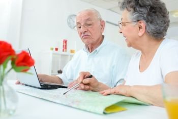 Elderly couple studying a map and using a notebook