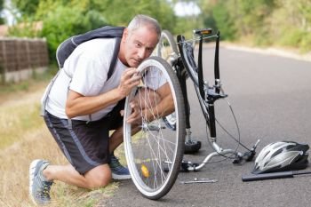 middle-age man fixing his bike outdoors