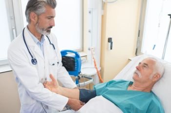 doctor checking senior mans blood pressure in hospital