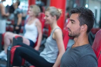 healthy man training in gym with people