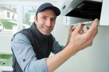 portrait of handyman fixing kitchen exhaust