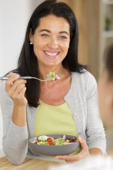 mature woman eating a salad with a friend