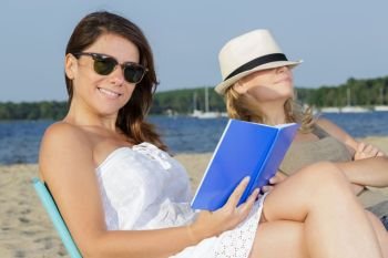 two female young adults reading books on beach