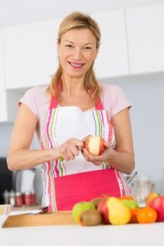 elder woman peeling apples in her kitchen