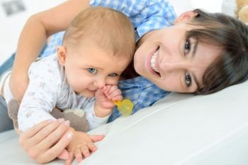 happy mother with baby lying on bed at home
