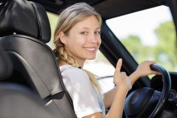 woman in drivers seat turning to make thumbs up gesture