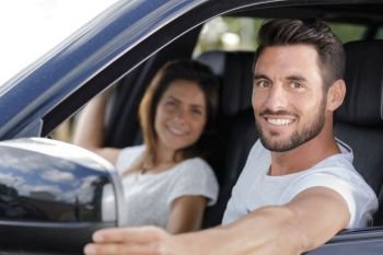 portrait of smiling man and woman in car
