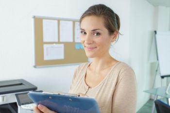 portrait of woman in an office holding a clipboard