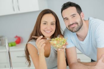 Couple sharing a salad in the kitchen