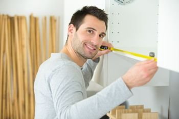 man measuring home furniture with measure tape