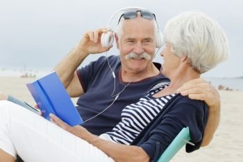 senior couple standing on beach listening to mp3 player