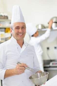 happy male chef whisking in bowl