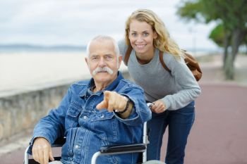 senior man in wheelchair in the park with daughter
