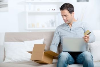 man with laptop credit card and cardboard boxes at home