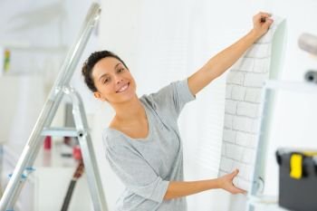 portrait of woman putting up wallpaper
