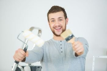 young excited man holding paint brush and smiling