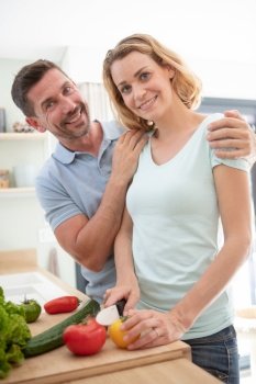 a happy couple preparing vegetable