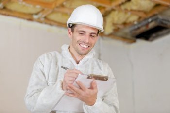 happy builder pointing finger and holding clipboard