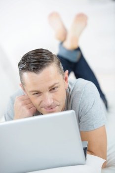 smiling man using laptop in a bed