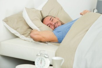 smiling man stretching in bed