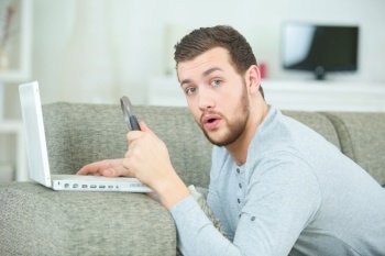 surprised man on sofa by the laptop