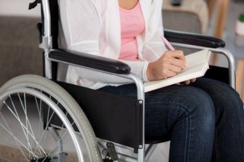 cropped image of woman in wheelchair writing in book