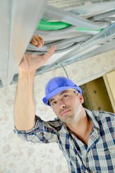 Builder holding cables at ceiling level