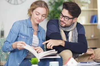 embracing young couple reading book on sofa